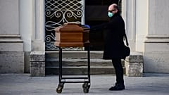 Un homme posant une main sur le cerceuil de sa mère à Bergame, le 20 mars 2020