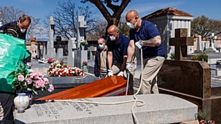 The coffin of a COVID-19 coronavirus victim is buried at Fuencarral cemetery in Madrid on March 29, 2020. 