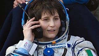 Italian astronaut Samantha Cristoforetti speaks on a satellite phone outside of the Soyuz AFP PHOTO / POOL / IVAN SEKRETAREV (Photo by IVAN SEKRETAREV / POOL / AFP)