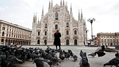 A woman stands in front of the Duomo cathedral, in downtown Milan, Italy.