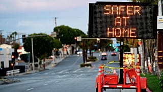 Panneau de signalisation routière recommandant indiquant "Plus en sécurité à la Maison" déployé dans les rues de Monterey Park en Californie, le 25 mars 2020.
