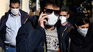 Un homme portant un masque de protection contre le nouveau coronavirus, parle sur son téléphone portable dans le centre de Téhéran, en Iran