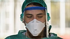 A healthcare worker dressed in protective gear waits for drivers at a drive-through testing. (Photo by CESAR MANSO / AFP)