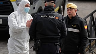 A member of UME, left, talks with a police officer at a ice-skating rink in Madrid, Spain, Tuesday, March 24, 2020.