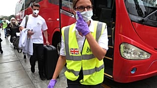 British travellers follow a British embassy employee before they are bused to the airport for flight home in Lima, Peru, Wednesday, March 25, 2020. (AP Photo/Martin Mejia)