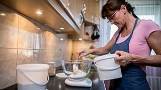 Zsuzsanna lisztet mér ki egy tálba házi kovászos kenyeréhez pécsi otthonában 2020. március 28-án.