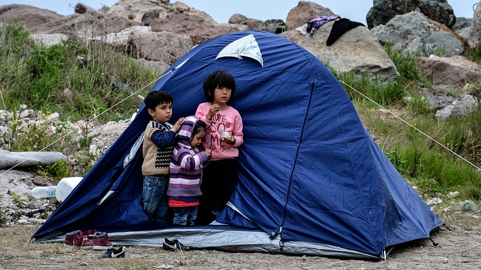 Children stand outside a tent in the village of Petra on the northeastern Aegean island of Lesbos, Greece, Friday, March 27, 2020