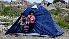 Children stand outside a tent in the village of Petra on the northeastern Aegean island of Lesbos, Greece, Friday, March 27, 2020