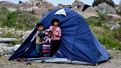 Children stand outside a tent in the village of Petra on the northeastern Aegean island of Lesbos, Greece, Friday, March 27, 2020