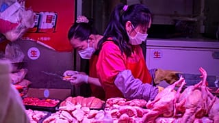 Employees wear face masks as they work at a poultry stall at a market in Beijing, Saturday, March 14, 2020