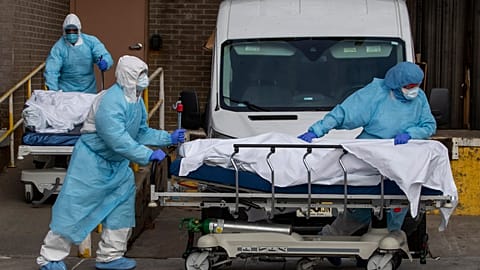 Medical personnel wearing personal protective equipment remove bodies from a medical centre in New York, 2020.
