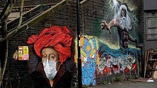 A mural by street artist Lionel Stanhope with a face mask reference to coronavirus next to one of his other works, at right, painted on a bridge wall in Ladywell
