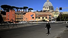 A woman walks with St Peter's Basilica in the background in Rome on April 6, 2020