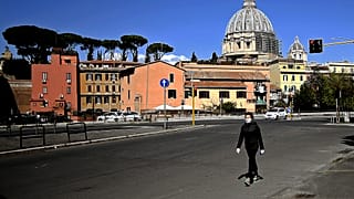 A woman walks with St Peter's Basilica in the background in Rome on April 6, 2020