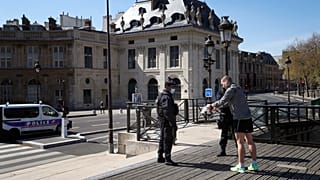 Полицейский проверяет у жителя Парижа разрешение на выход из дома. 