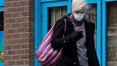 Une femme porte un masque et consulte son téléphone, le mardi 24 mars 2020, dans le quartier de Capitol Hill à Seattle.