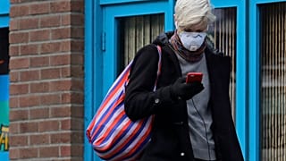 Une femme porte un masque et consulte son téléphone, le mardi 24 mars 2020, dans le quartier de Capitol Hill à Seattle.