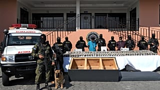 Two members of the Mara 18 gang are escorted by members of the National Force Against Gangs next to drug packages 