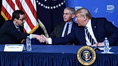 Donald Trump, amerikai elnök John Mascolának, a Vakcinakutató Központ igazgatójának a kezét rázza épp Dr. Fauci előtt