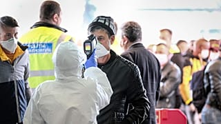 A Romanian seasonal worker has his temperature checked outside the airport in Cluj