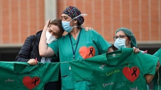 Healthcare workers (R) confort the wife of Esteban, a male nurse that died of the coronavirus