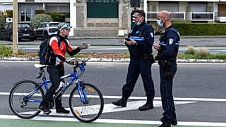 A cyclist is stopped by French police controlling the lockdown at La Baule in western France, Easter Monday, April 13, 2020.