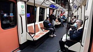 Commuters wearing face masks sit on a train at the Atocha Station in Madrid on April 13, 2020 as some companies resume operations amid the coronavirus lockdown. 