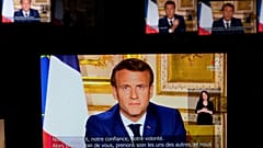 French President Emmanuel Macron is seen on multiple monitors in Paris, as he speaks from the Elysee Palace during a televised address to the nation on April 13, 2020.