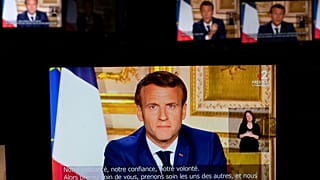 French President Emmanuel Macron is seen on multiple monitors in Paris, as he speaks from the Elysee Palace during a televised address to the nation on April 13, 2020.