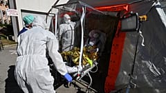 Firefighters exit a patient on a sarcophagus stretcher from a medical tent outside the Montpellier University Hospital which houses a COVID-19 test center on April 14, 2020 