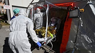 Firefighters exit a patient on a sarcophagus stretcher from a medical tent outside the Montpellier University Hospital which houses a COVID-19 test center on April 14, 2020 