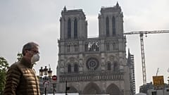 Um homem de máscara passa diante da catedral de Notre-Dame, em Paris