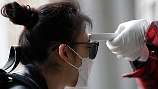 A voter has her temperature checked upon her arrival at a polling station in Seoul, South Korea, Wednesday, April 15, 2020.