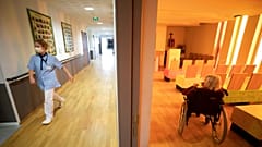 A nurse walks in a corridor of a nursing home as a resident sits in a chapel during a COVID-19 testing session in Bergheim, eastern France, Tuesday April 14, 2020
