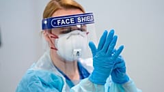 In this Thursday, April 16, 2020 photo, a member of staff receives training on how to put on and remove PPE