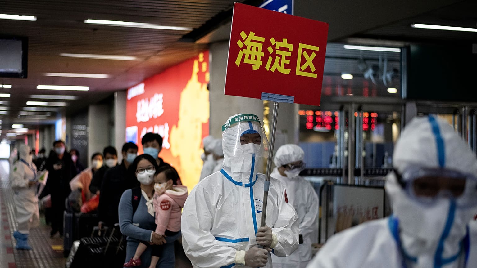 Employés de sociétés transports encadrant des voyageurs en provenance de Wuhan pour les conduire vers des lieux de quarantaine à leur arrivée à Pékin, le 15 avril 2020.