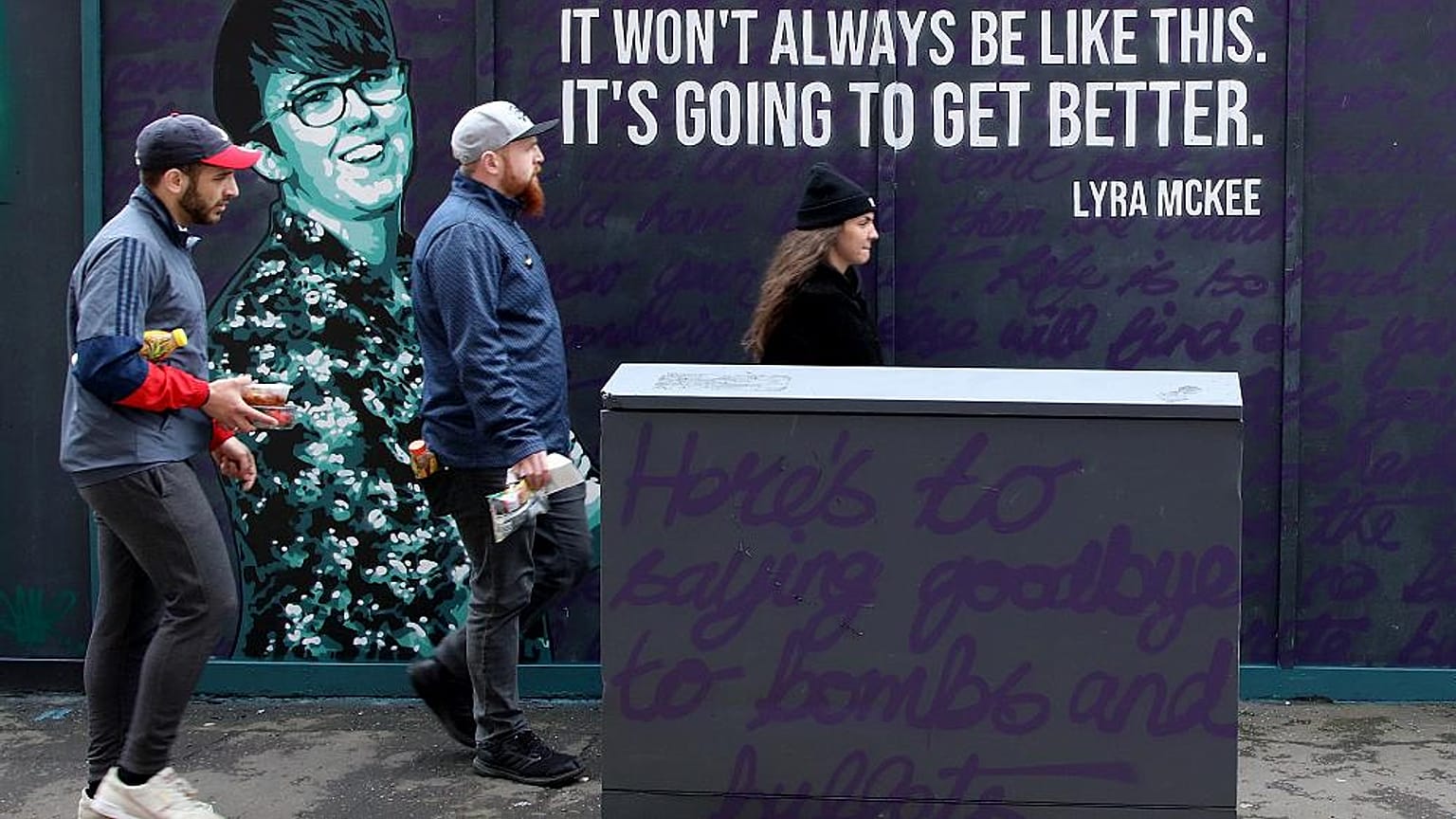 Residents walk past a newly painted mural featuring murdered journalist Lyra McKee in central Belfast on May 7, 2019
