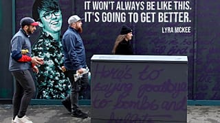 Residents walk past a newly painted mural featuring murdered journalist Lyra McKee in central Belfast on May 7, 2019