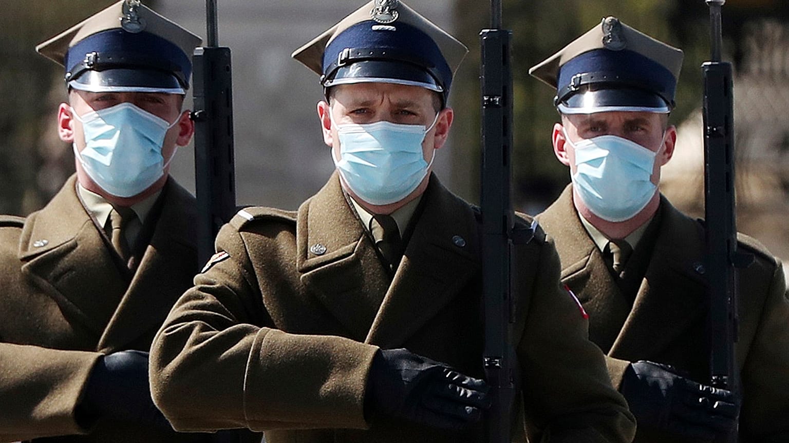 A military guard of honor wear face masks against the spread of the coronavirus by the Unknown Soldier's Tomb in Warsaw, Poland, Thursday, April 16, 2020