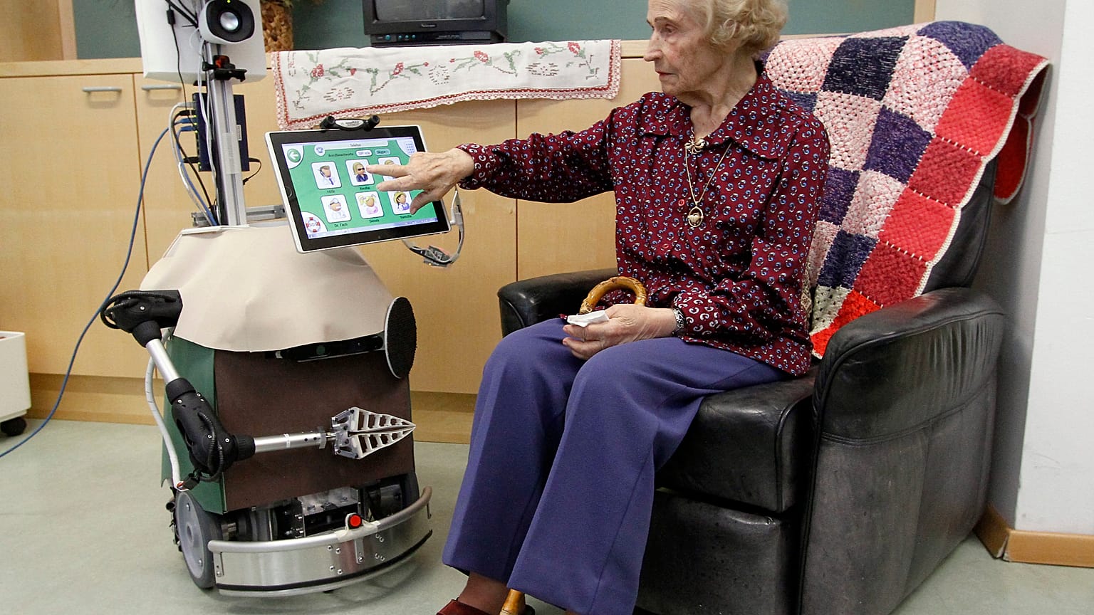 An old woman poses with care robot during a demonstration in Vienna, Austria, Thursday, March 14, 2013. 