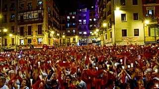 Los juerguistas sostienen velas y pañuelos rojos cantando ''Pobre de Mi'' para cerrar San Fermín 2019 el 15 de julio en Pamplona.