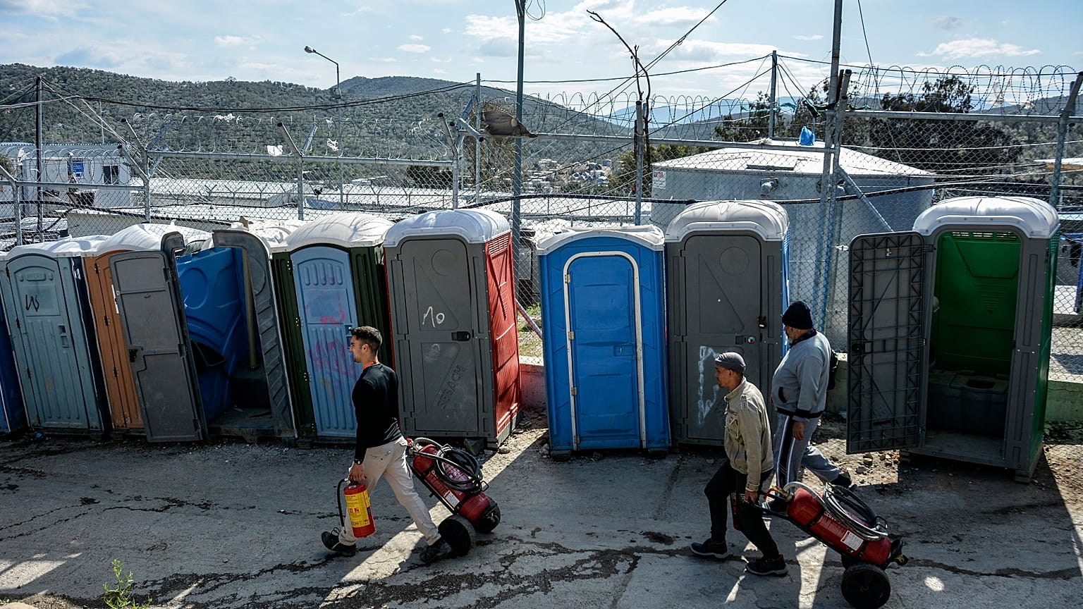 Migrants pull fire extinguishers in Moria refugee camp on the northeastern Aegean island of Lesbos, Greece, Monday, March 16, 2020