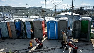 Migrants pull fire extinguishers in Moria refugee camp on the northeastern Aegean island of Lesbos, Greece, Monday, March 16, 2020