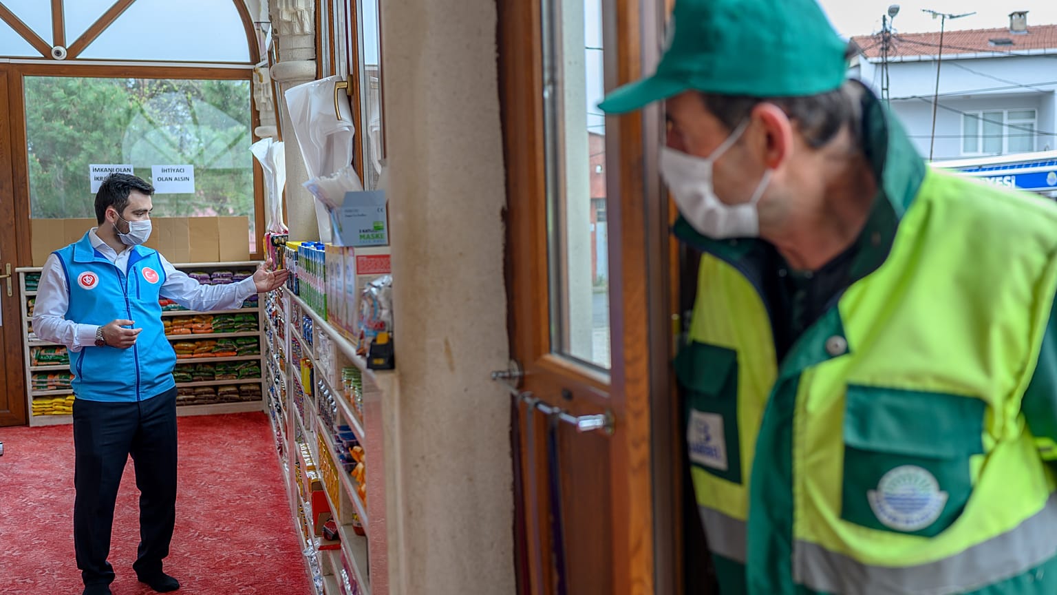 Abdulsamet Cakir (L), 33, imam of the Dedeman mosque works as a man waits at the entrance of the Dedeman mosque on April 21, 2020