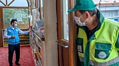 Abdulsamet Cakir (L), 33, imam of the Dedeman mosque works as a man waits at the entrance of the Dedeman mosque on April 21, 2020