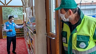 Abdulsamet Cakir (L), 33, imam of the Dedeman mosque works as a man waits at the entrance of the Dedeman mosque on April 21, 2020