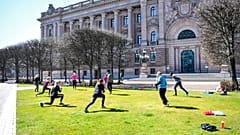 People exercise on a lawn, keeping distance amid the coronavirus disease (COVID-19) outbreak, outside the old parliament building in central Stockholm, Sweden, Tuesday, April 