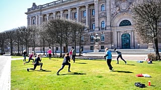 People exercise on a lawn, keeping distance amid the coronavirus disease (COVID-19) outbreak, outside the old parliament building in central Stockholm, Sweden, Tuesday, April