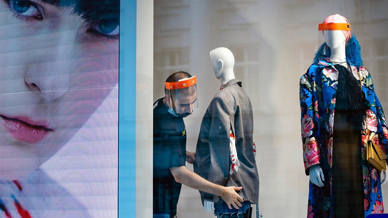 A fashion shop employee wearing a face mask adjusts a mannequin in Moscow, Russia, Tuesday, April 14