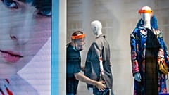 A fashion shop employee wearing a face mask adjusts a mannequin in Moscow, Russia, Tuesday, April 14
